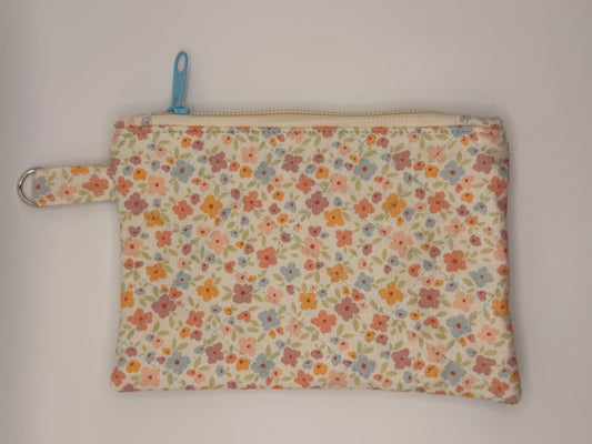 Floral-patterned pouch with a blue zipper on a cream background