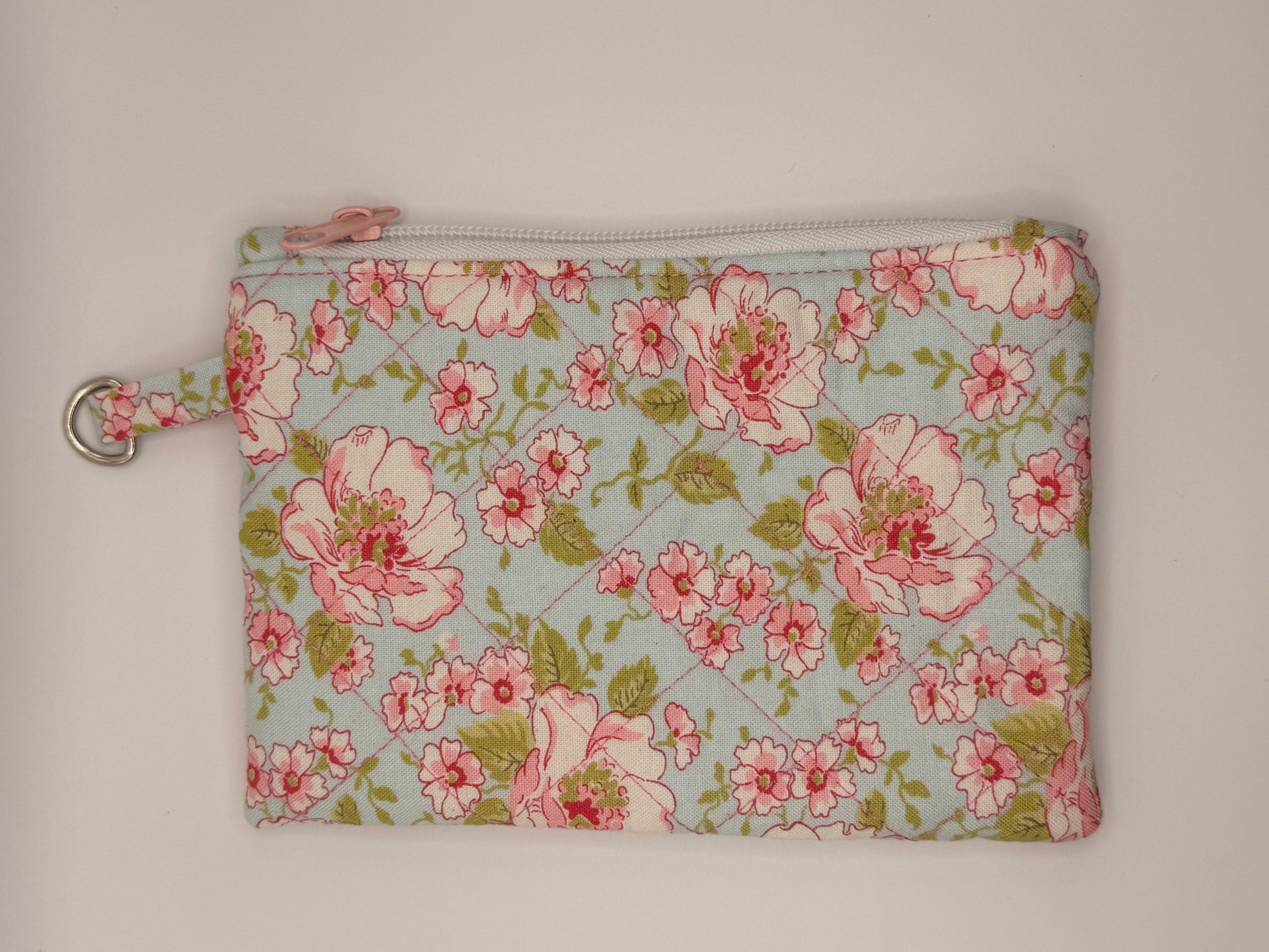 Floral-patterned pouch with pink flowers on a light blue background