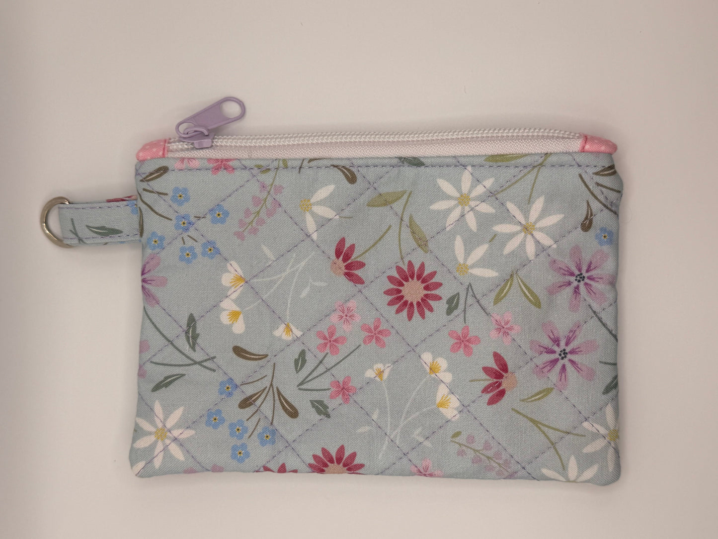 Floral-patterned pouch with a zipper on a light blue/gray background